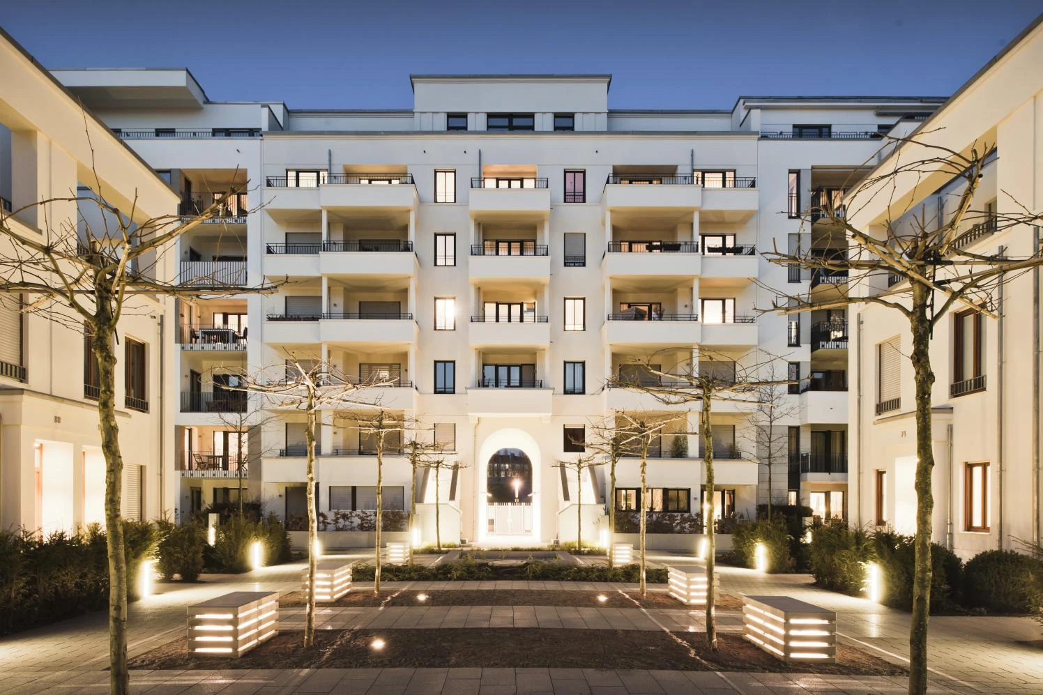 Wohnquartier mit beleuchtetem Innenhof am Abend
